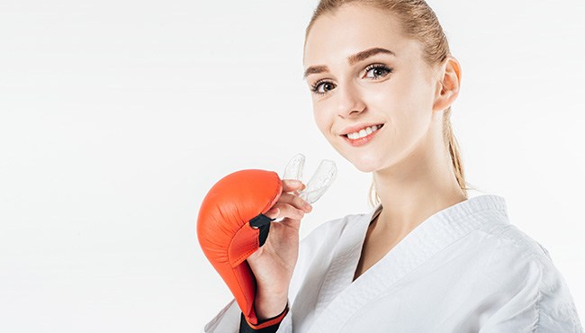 A female athlete holding an athletic mouthguard