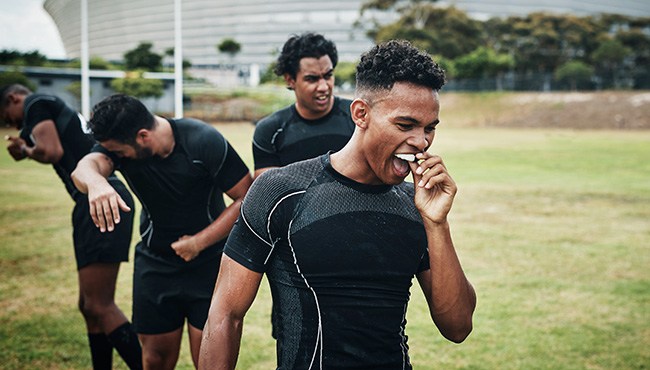 Male athlete inserting a mouthguard while on the field