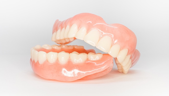 Top arch of dentures resting on lower set on white background