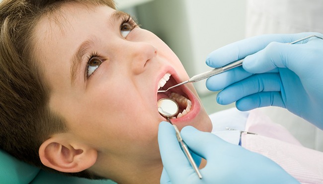 A boy lying in a treatment chair awaiting dental sealants