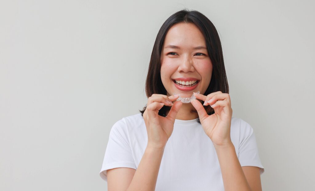 Woman smiling while holding clear retainer